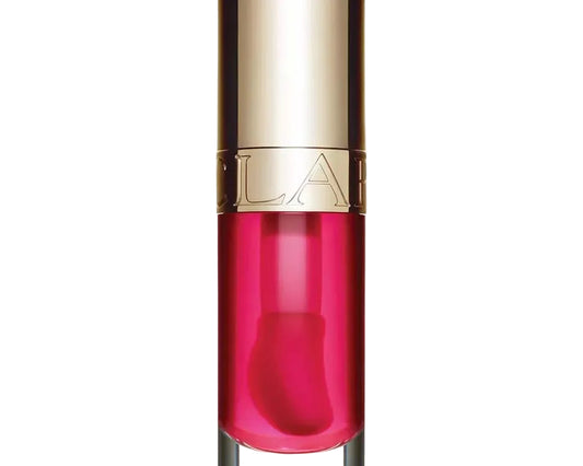 A clear cylindrical cosmetic bottle filled with vivid pink liquid, topped with a reflective metallic gold cap. The brand name 'CLARA' is embossed on the gold band around the middle of the bottle.